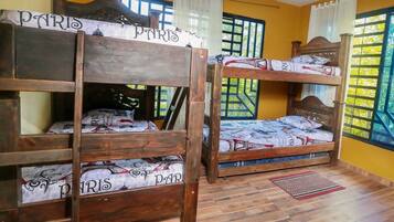 Camas literas con ropa de cama con temática parisina, pisos de madera y ventanas con cortinas.