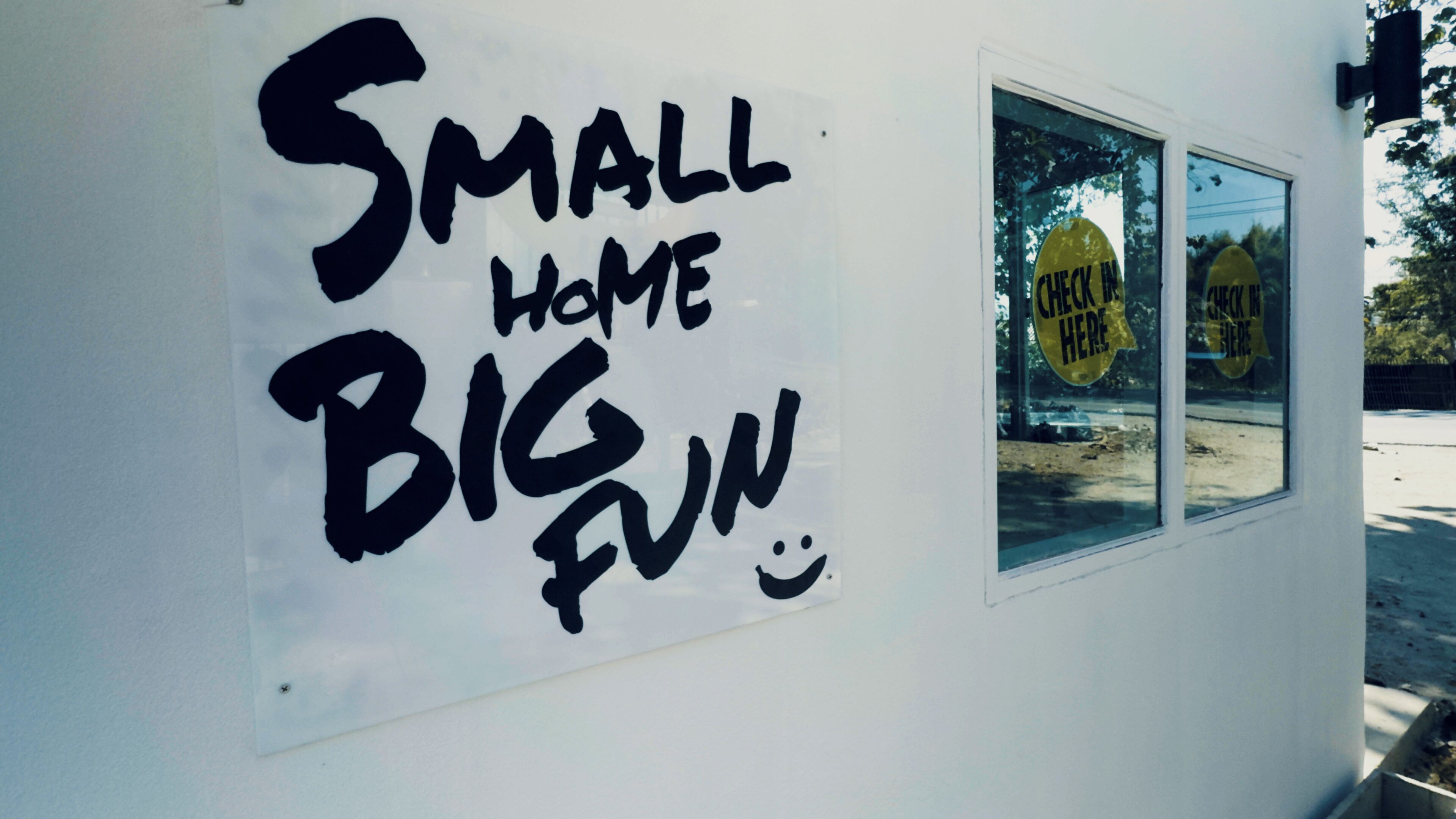 Un letrero en un edificio que dice 'SMALL HOME BIG FUN' con una carita sonriente.