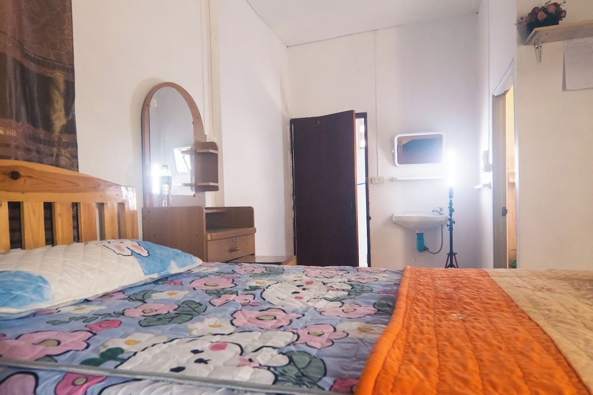 A bedroom with a wooden bed, a dresser, a mirror, a sink, and a door.