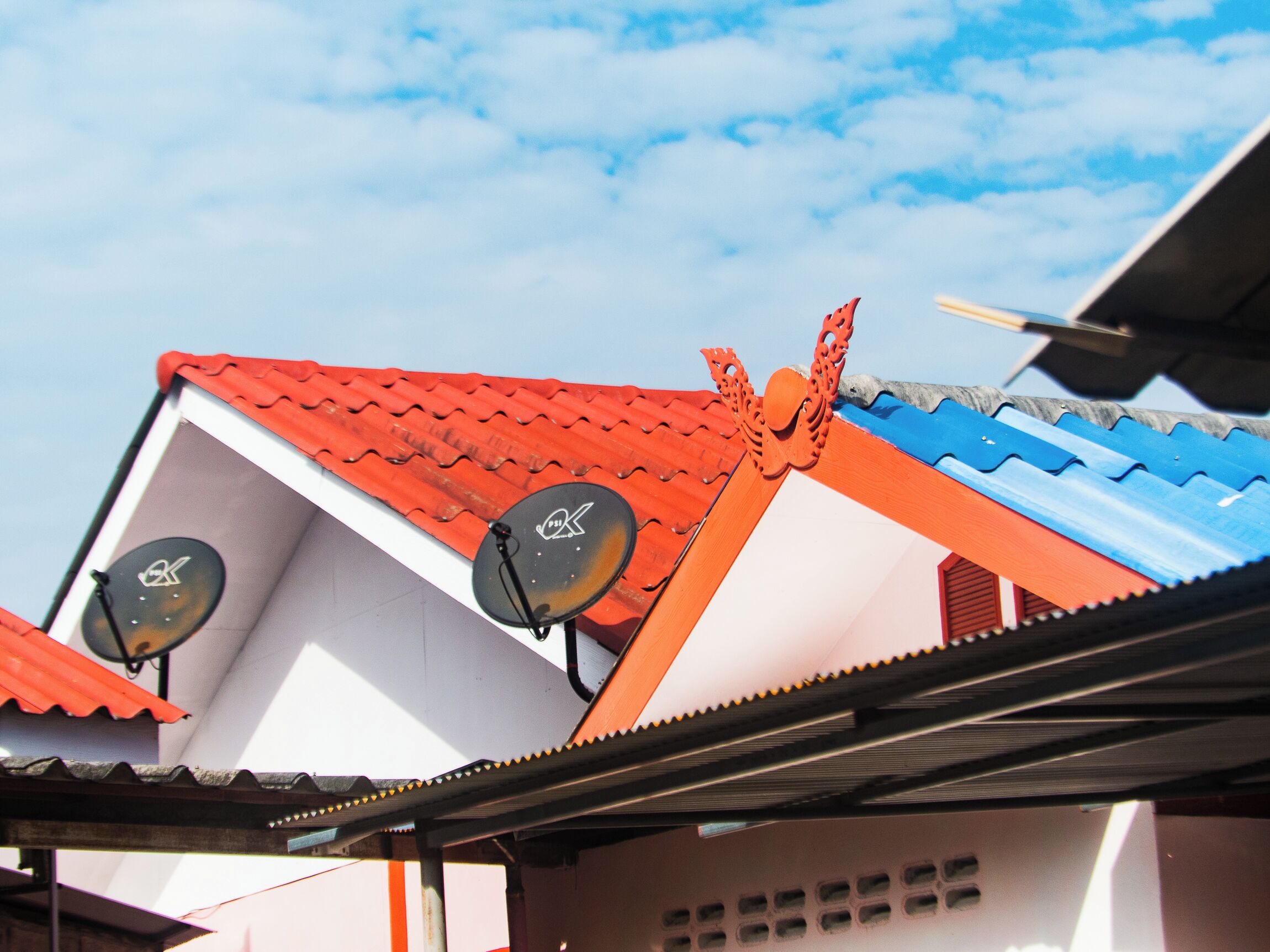 A building with a red tiled roof and two satellite dishes.