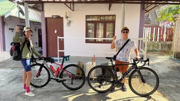 Un espacio al aire libre cubierto con bicicletas y una maleta, indicando un servicio de alquiler o viajes.