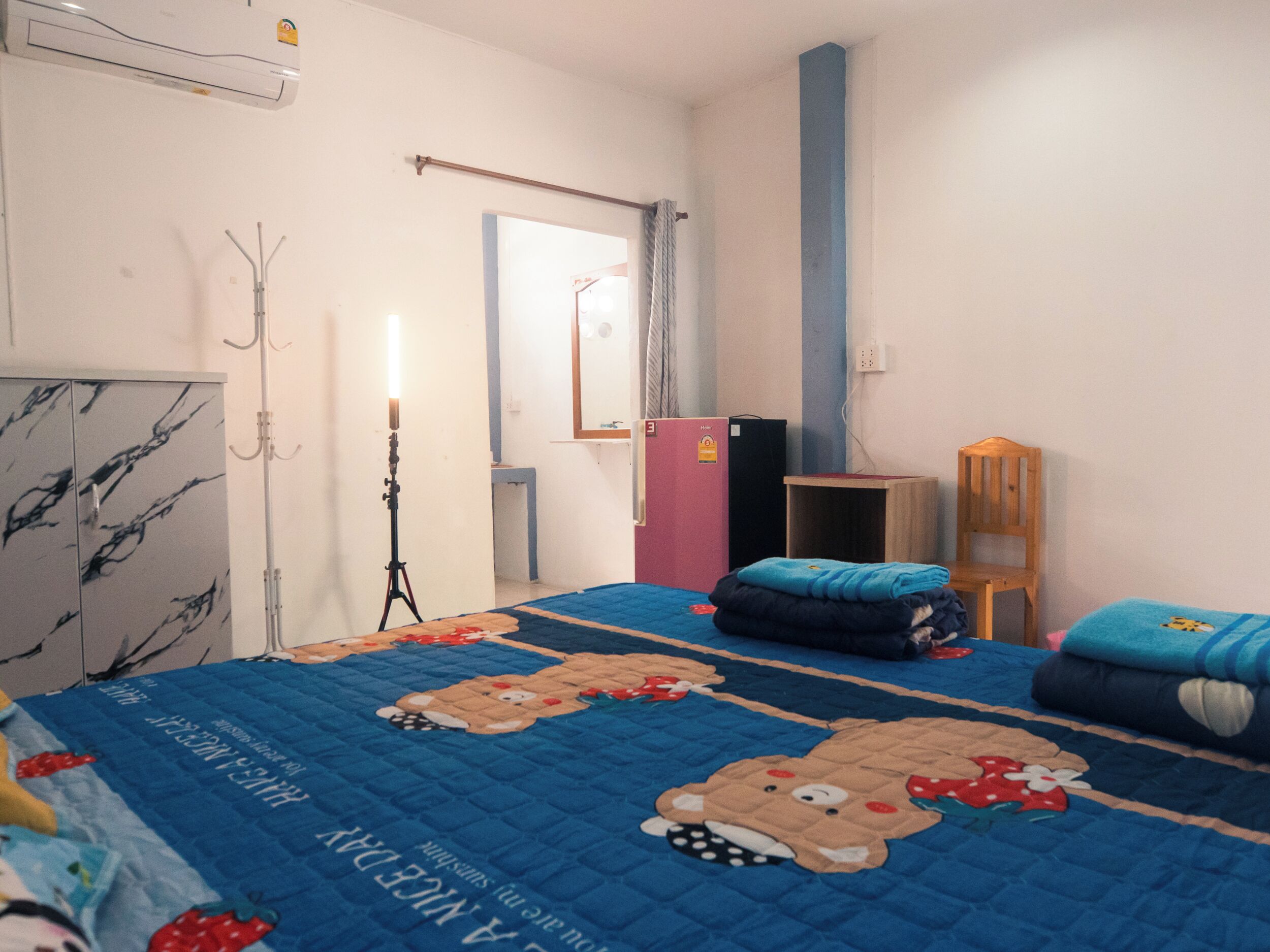 A bedroom with a bed, a wardrobe, a desk, a chair, and a mirror.