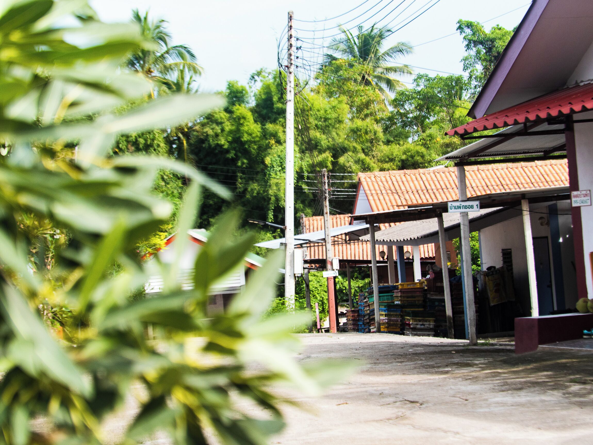 A street view with a building that has a tiled roof and a sign indicating a location.