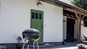 Una parrilla de barbacoa frente a un edificio con una puerta verde y un porche cubierto.