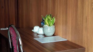 Een houten receptiebalie met een bloempot, een klein vaasje en een menukaart.