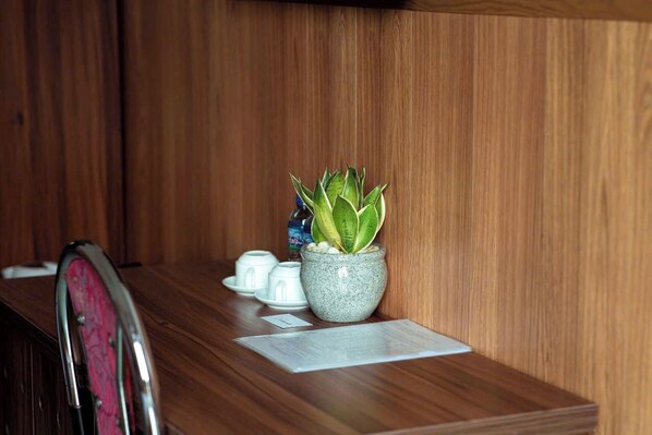 Un mostrador de recepción de madera con una planta en maceta, un pequeño jarrón y un menú.