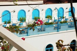 Un edificio blanco con ventanas en arco azules y un balcón con barandillas azules.
