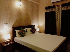Habitación de hotel con una cama grande, dos lámparas de noche, una mesita de noche y aire acondicionado instalado en la pared.