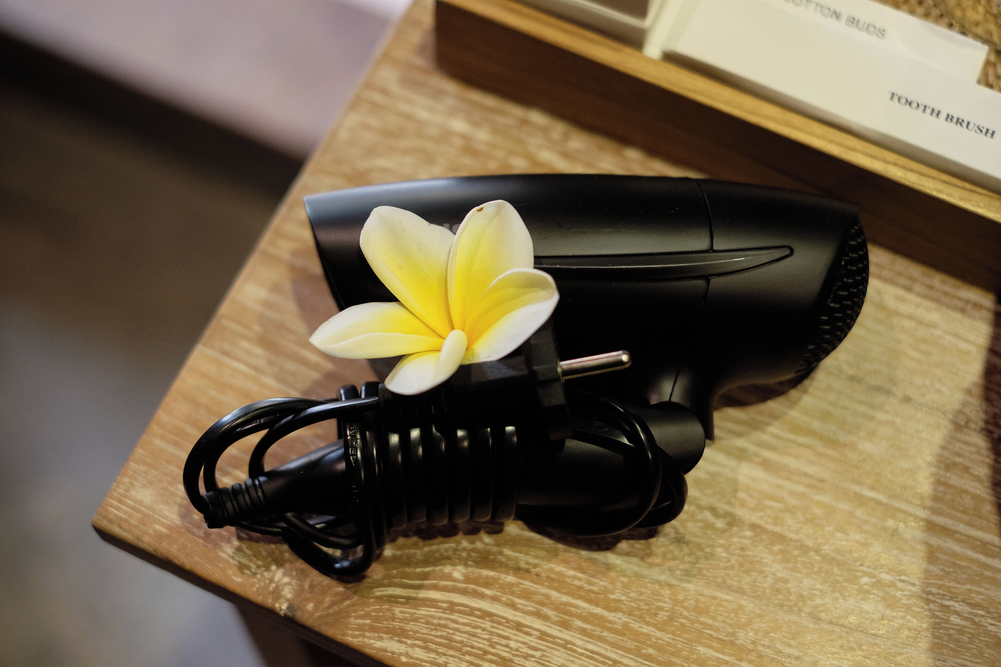 A hair dryer with a flower on a wooden surface.