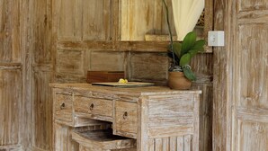 A rustic wooden vanity with a mirror, a small stool, and a potted orchid. - Astala Ubud Villa (Ubud)