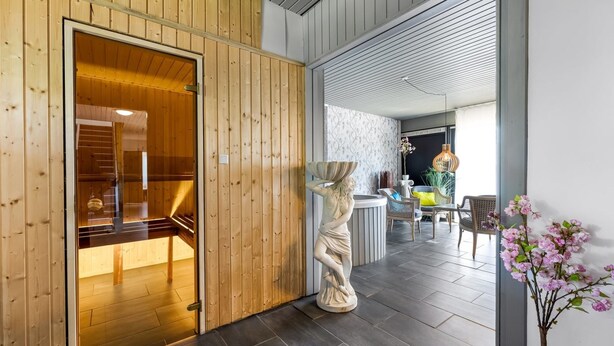 Un interior de madera con un mostrador de recepción, una estatua y una zona de estar con sillas y una mesa.