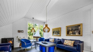 Una sala de estar moderna con chimenea, muebles azules y ventanas amplias.