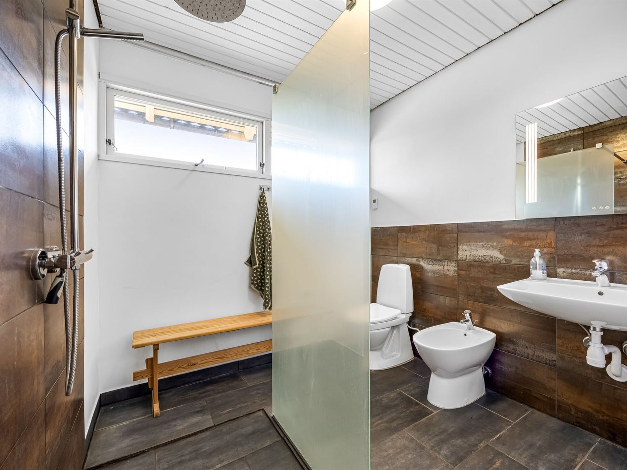 A modern bathroom with a shower, toilet, bidet, and sink.