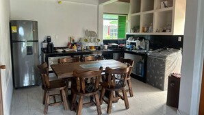 A compact kitchen with a dining table and chairs, a refrigerator, and a sink.