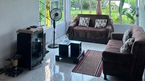 A living room with a TV, two sofas, a fan, and a small cabinet.