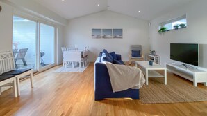 A spacious living room with a large TV, a sofa, and a dining area with a table and chairs.