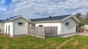 A two-story house with a grey roof and white siding, a fenced backyard, and a clear sky.