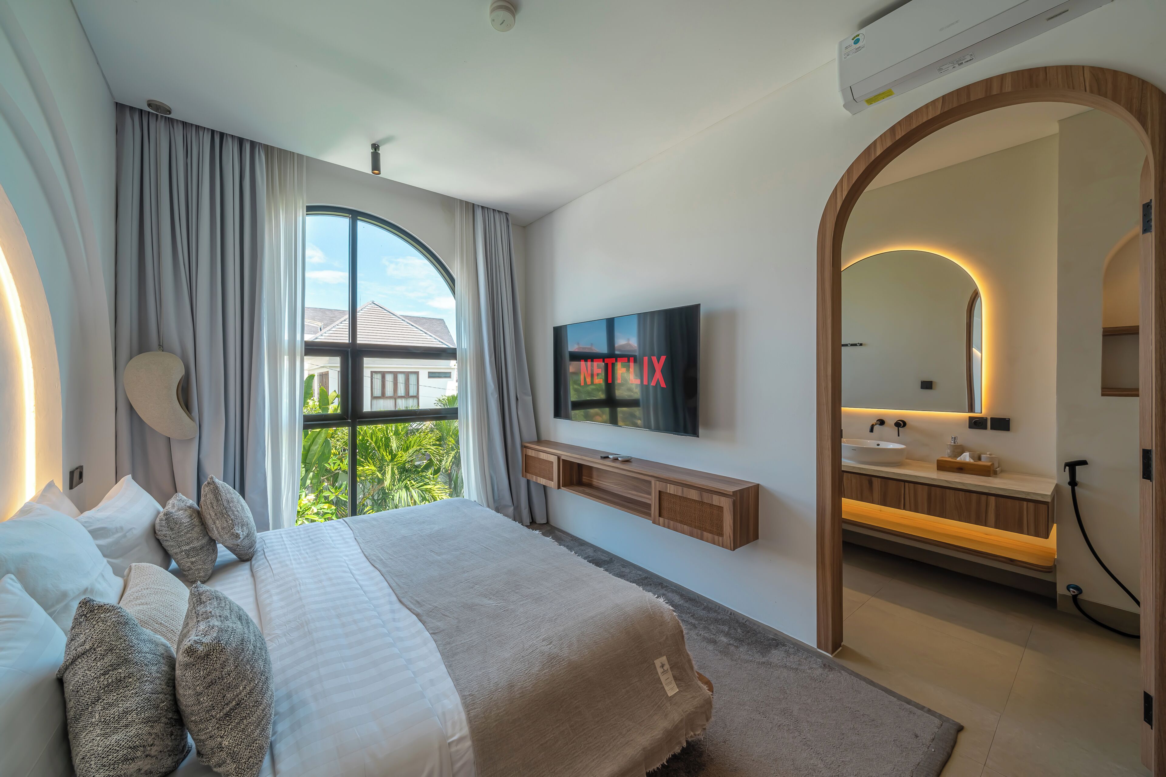 Una camera da letto moderna con un ampio letto, una televisione, un bagno con lavabo e vista sul verde.
