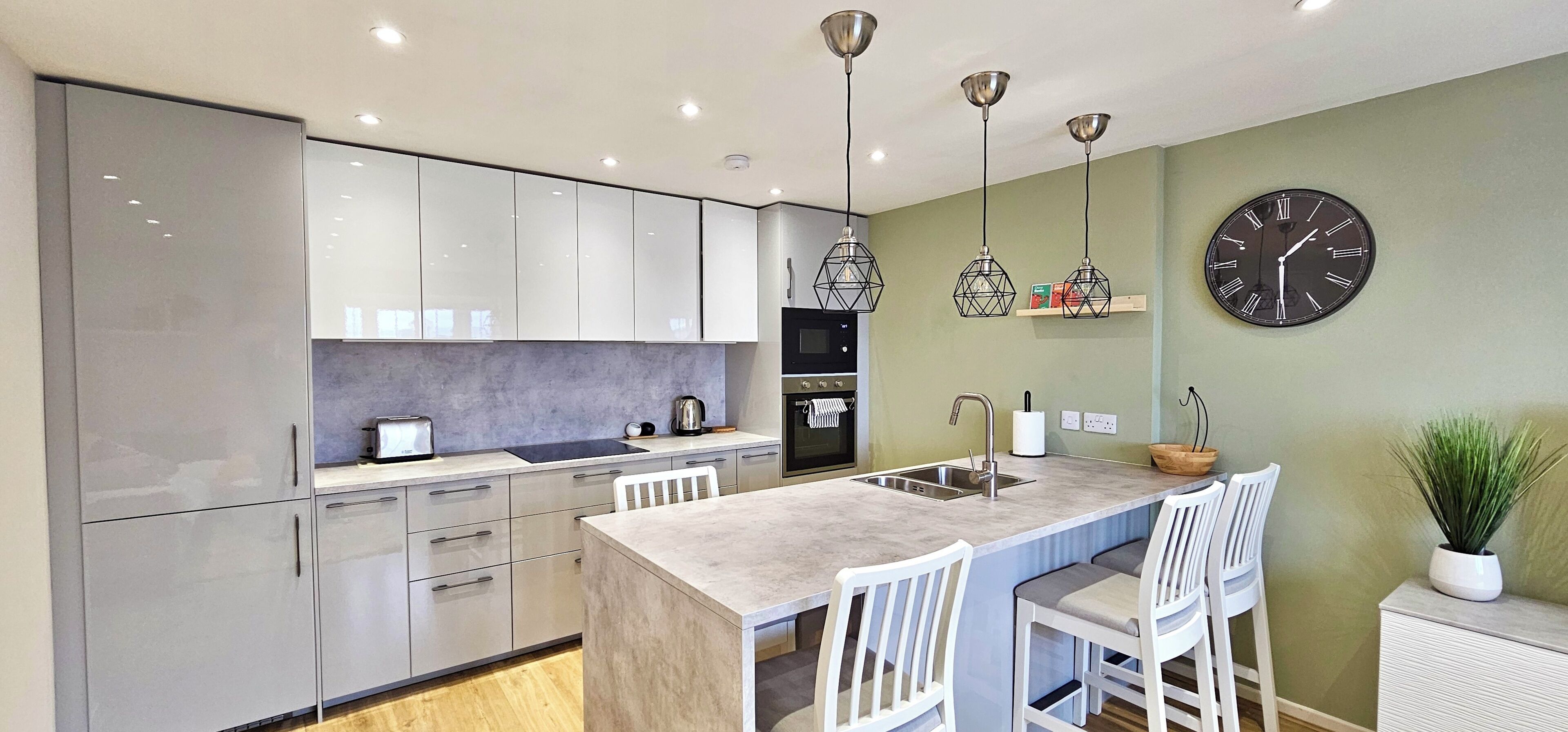 A modern kitchen with a central island, white cabinetry, and pendant lighting.