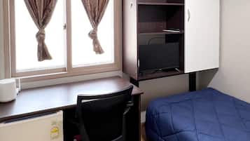 Une pièce de taille modeste, comprenant un bureau, une chaise et un lit.