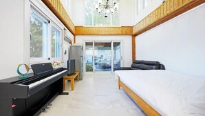 Une chambre moderne avec un piano, un lit, une télévision et un balcon offrant une vue agréable.