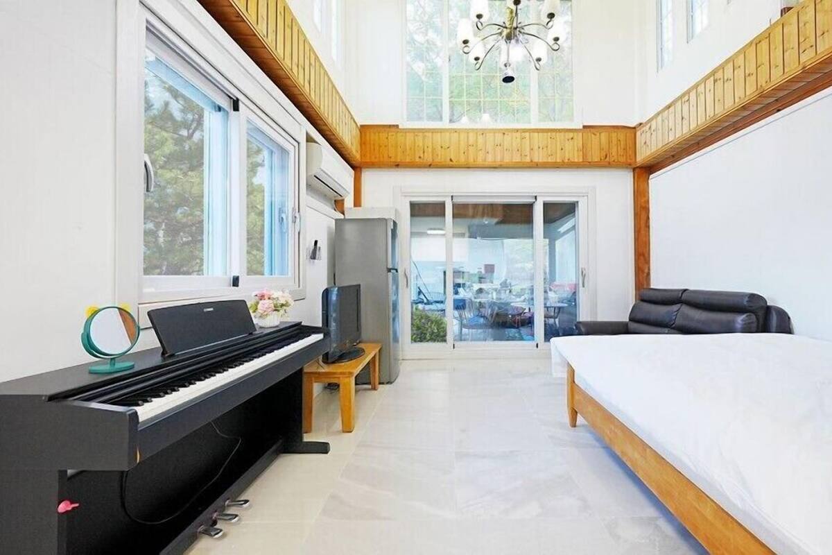 Une chambre moderne avec un piano, un lit, une télévision et un balcon offrant une vue agréable.