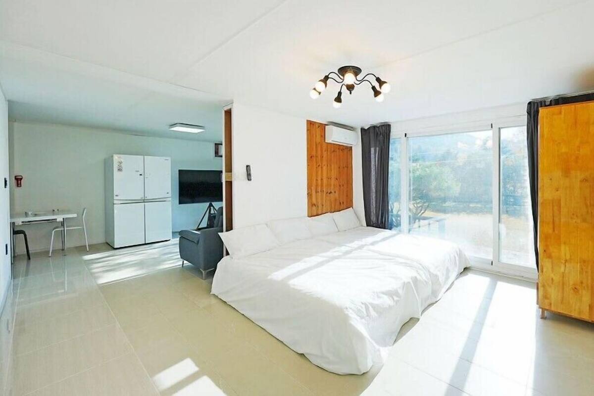 Une chambre moderne avec un grand lit, un bureau et un coin cuisine.