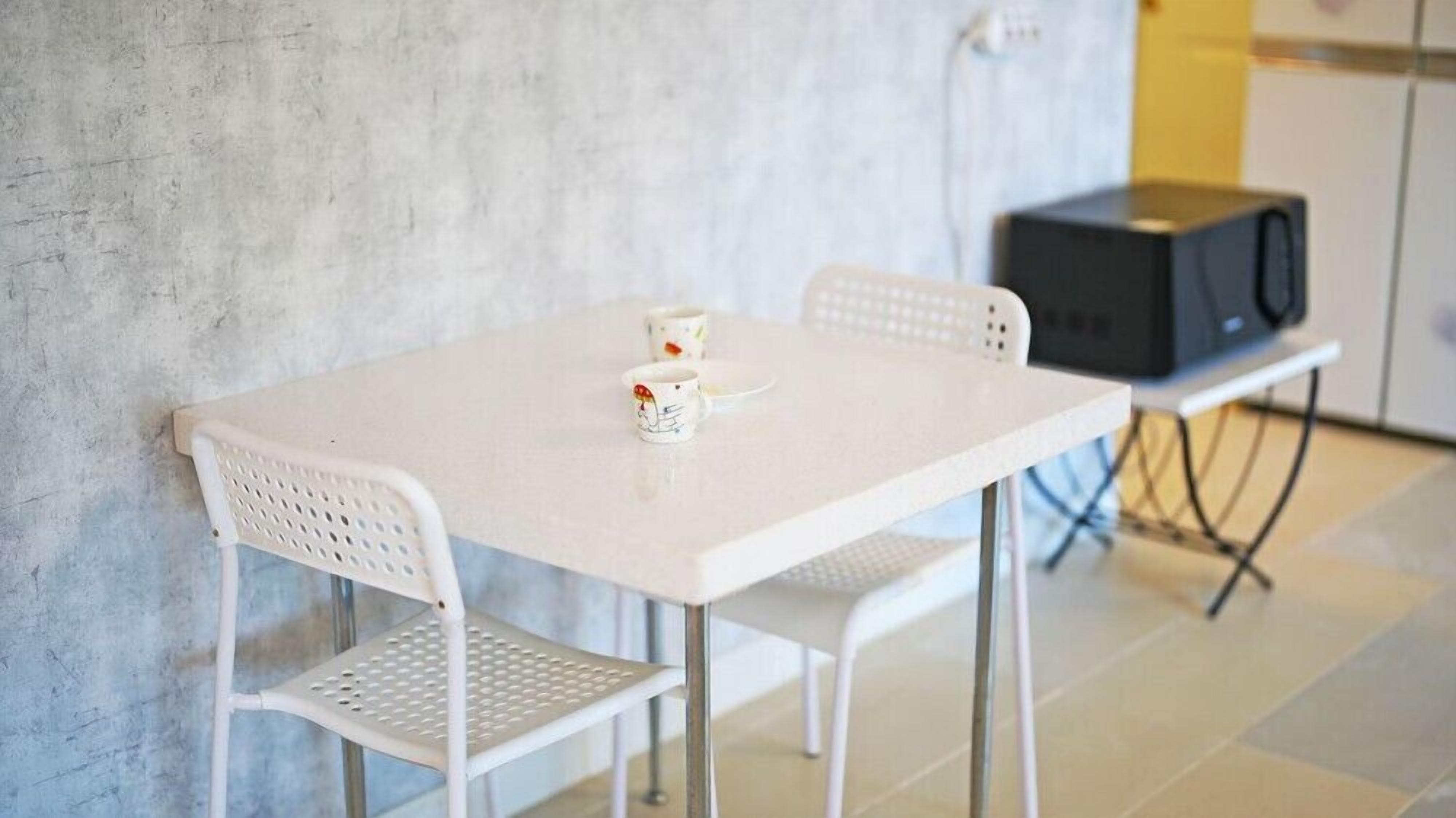 A white table with two chairs and two cups on it.