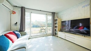 Un salon avec un canapé, un téléviseur et des portes-fenêtres coulissantes donnant sur un balcon.