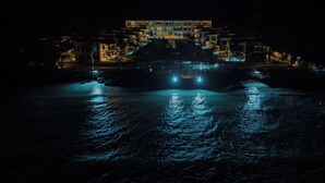 A modern building with a swimming pool at night, illuminated by lights.