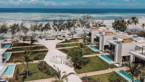 A resort with modern architecture, multiple swimming pools, and a beach view.