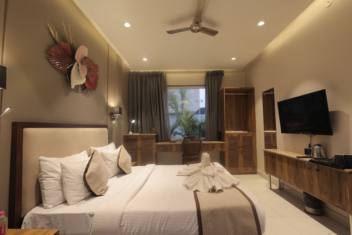 A hotel room with a bed, a desk, a television, and a window with curtains.