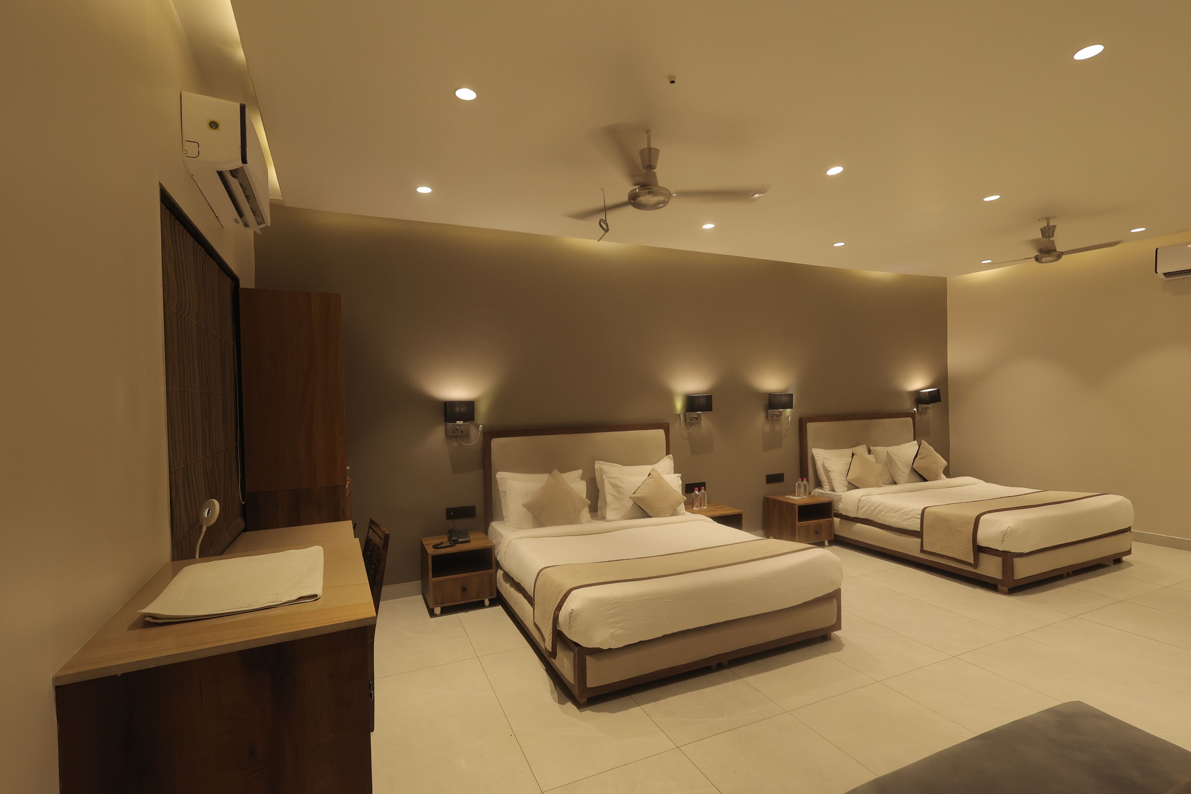 A modern bedroom with two beds, nightstands, and a desk.