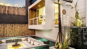 A modern outdoor living area with a pool, a built-in seating area, and a vertical garden. - Villa Mugiwara by BaliSuperHost (Ubud)