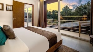 A bedroom with a large bed, a balcony with a railing, and a view of palm trees. - Villa Mugiwara by BaliSuperHost (Ubud)