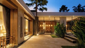 Una casa moderna con fachada de vidrio, terraza de madera y ambiente interior luminoso.