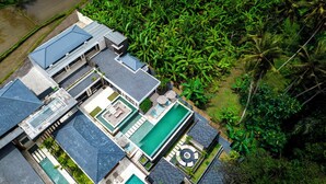 Un resort moderno con varias edificaciones, piscina y exuberante vegetación tropical.
