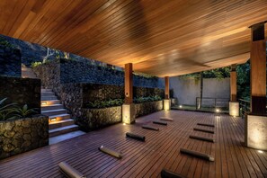 Une terrasse en bois avec des murs, des marches et des piliers en pierre.