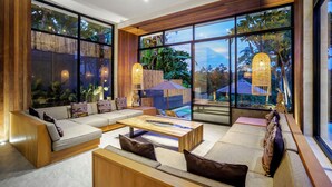 Un salón moderno con ventanas amplias, un conjunto de sofá de madera y una mesa de comedor.