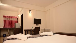 A hotel room with a bed, a desk with a chair, a television, and a shower area. - JAS HOLIDAYS MORJIM (Morjim)