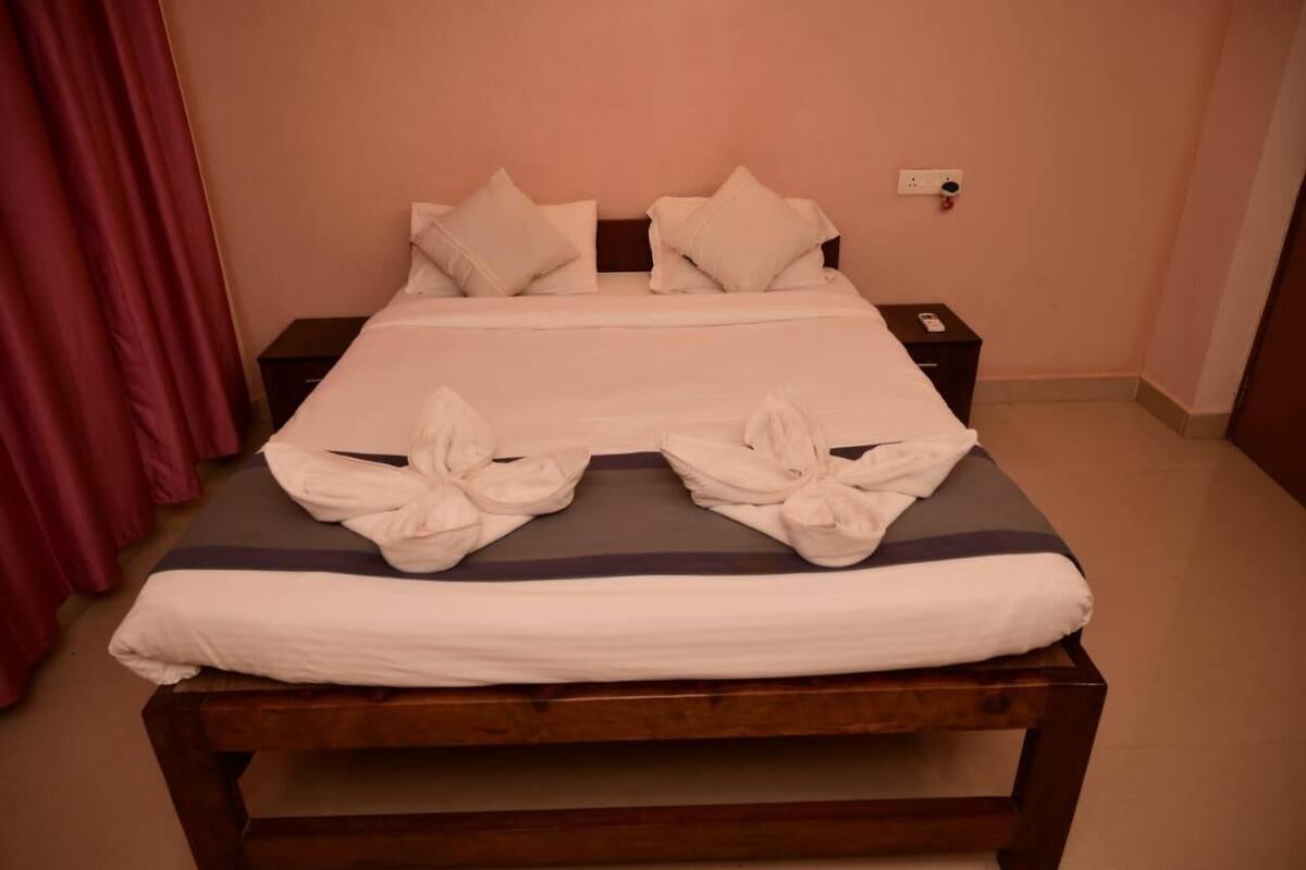 A neatly made bed with white linens and two towels folded on the bed.