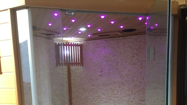 A sauna with a glass door, wooden benches, and purple LED lights on the ceiling. - In the Luberon, indulge yourself with a private spa and sauna (Reillanne)