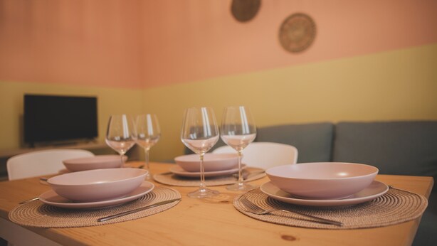 A dining table set with pink bowls, wine glasses, and placemats. - "Cozy Apartment Near the Sea - Ideal for Holidays" (Balestrate)