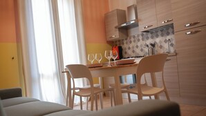A modern kitchen with wooden cabinets, a dining table with chairs, and a window with curtains. - "Cozy Apartment Near the Sea - Ideal for Holidays" (Balestrate)