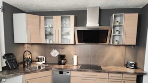 Une cuisine moderne avec des meubles en bois, un four à micro-ondes encastré et un lave-vaisselle.