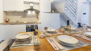 Une cuisine moderne dotée d’une cuisinière intégrée, d’une hotte en acier inoxydable et d’un petit îlot central avec un évier.
