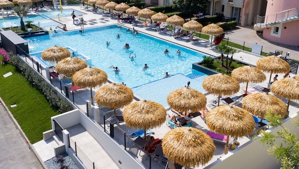 Une piscine dotée de plusieurs couloirs, entourée de chaises longues et d’ombrelles en chaume.