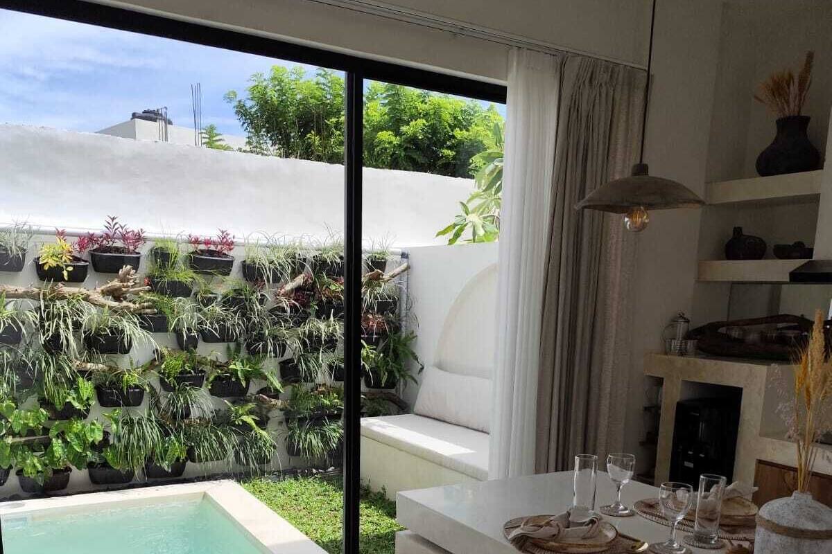 A modern kitchen with a large window, a dining area with a white table, and a small pool.