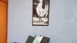 Une chambre à coucher avec un lit, un tableau encadré au mur et une table de chevet avec une lampe.