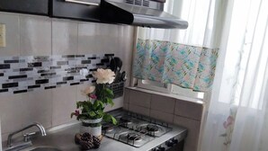 Une cuisine avec des meubles de couleur sombre, un évier en acier inoxydable, une cuisinière à gaz et un dosseret carrelé.